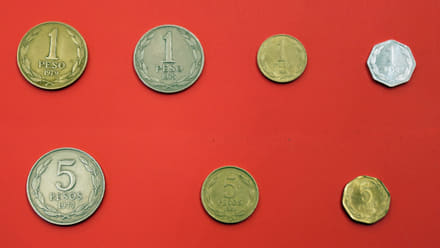 Monedas chilenas de 1 y 5 pesos de distintas épocas, anversos y reversos sobre fondo neutro