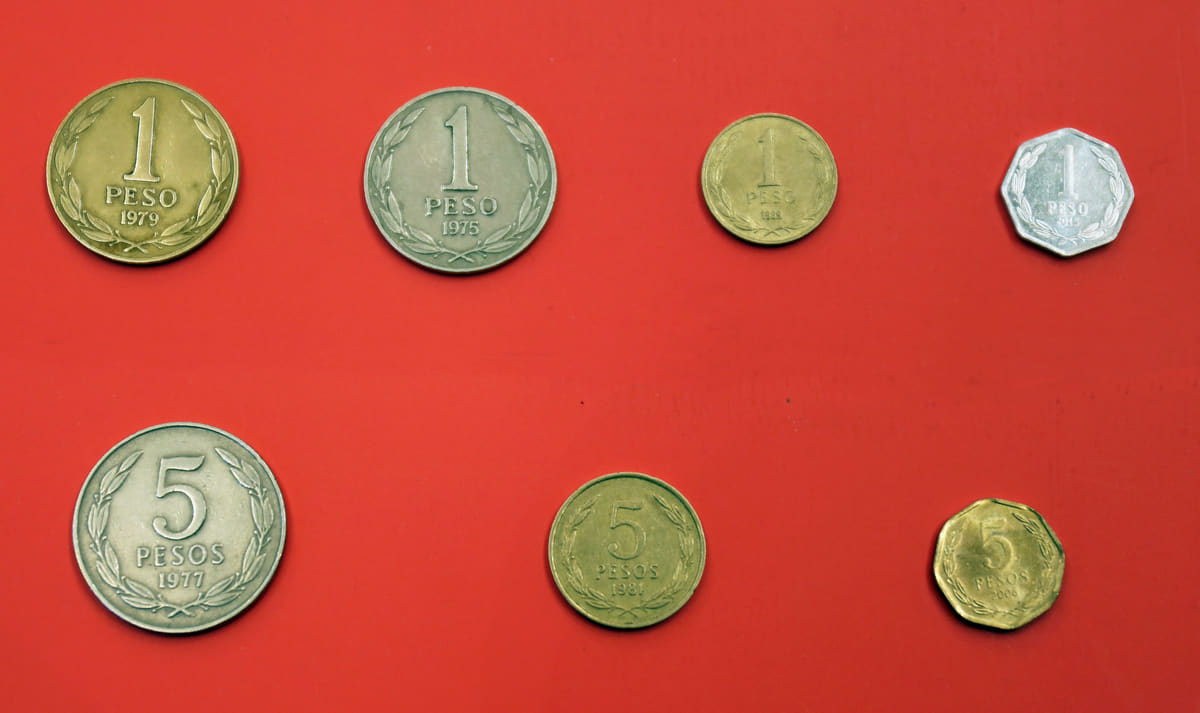 Monedas chilenas de 1 y 5 pesos de distintas épocas, anversos y reversos sobre fondo neutro