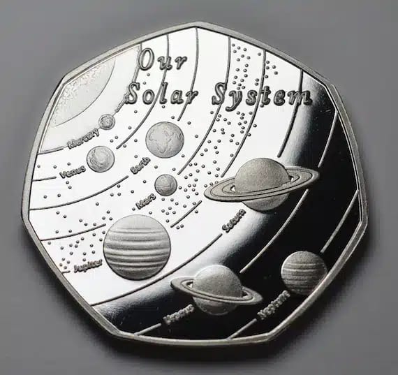 Medalla heptagonal de plata con el Sistema Solar, órbitas y planetas etiquetados sobre fondo gris