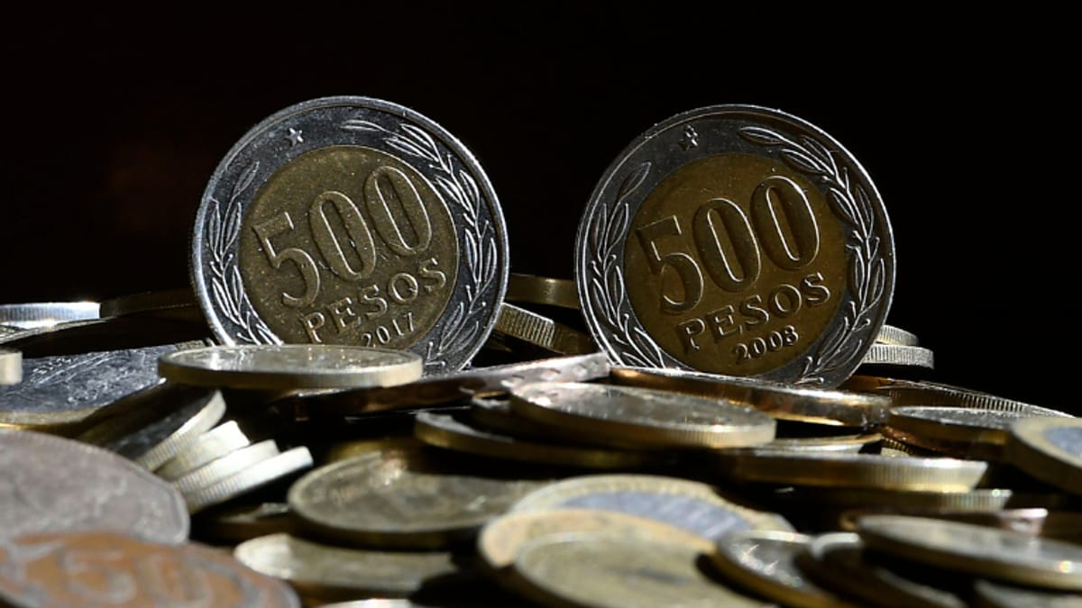 Dos monedas bimetálicas chilenas de 500 pesos de perfil sobre un montón de monedas, con los años visibles en el reverso
