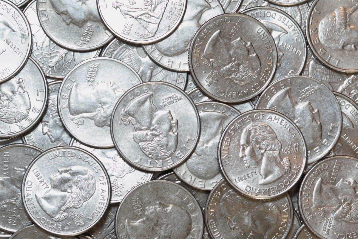 Manos de coleccionista revisando monedas de 25 centavos estadounidenses