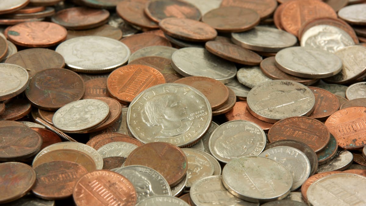 Montón de monedas estadounidenses circuladas —centavos, nickels, dimes y quarters— amontonadas en primer plano