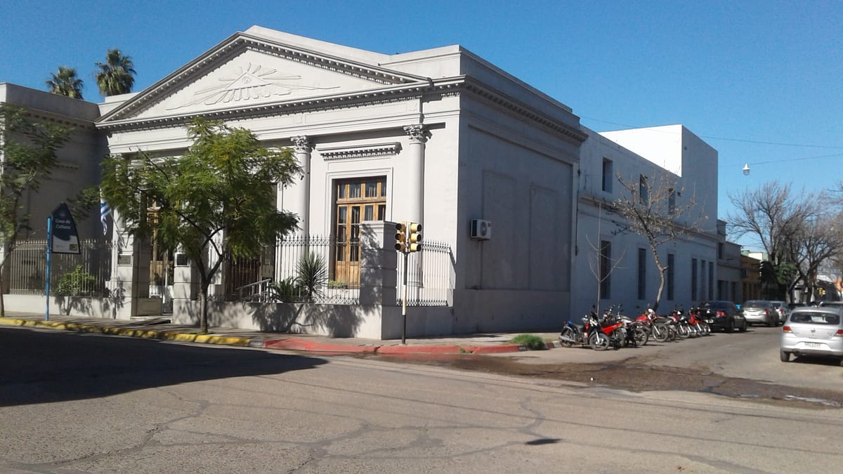 Fachada neoclásica de la Casa de Cultura de Paysandú, con columnas, frontón y bandera uruguaya